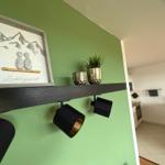 Grunder Wohnbereich mit grünem Wandbild und Küchenbereich im Hintergrund.