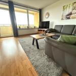 Wohnzimmer mit Sofa, Couchtisch und Balkon. Wandbild und Uhr sind sichtbar.