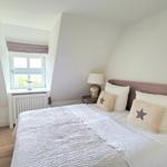 Schlafzimmer mit Bett, Nachttischen und Fenster