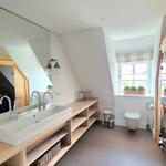 Badezimmer mit Waschbecken, Spiegel und Toilette unter Dachschrägen