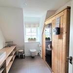 Badezimmer mit Waschbecken, Toilette und Holz-Sauna.