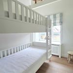 Ein Schlafzimmer mit Doppelstockbett, Holzboden und Fenster mit Rollladen.