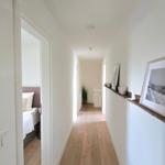 Flur mit Holzboden und Bildern an der Wand. Im Hintergrund ist ein Schlafzimmer sichtbar.