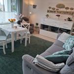 Wohnzimmer mit Sofa, Esstisch und Blick auf Balkon.