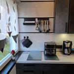 Küche mit Arbeitsplatte, Kaffeemaschine und Küchenutensilien an der Wand.