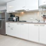 Moderne Küche mit weißen Schränken, Edelstahl-Kühlschrank und Küchenzeile.