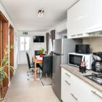 Küche mit Arbeitsplatte, Kühlschrank, Herd und Esstisch mit Stühlen.