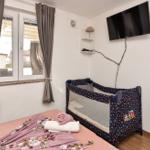 Zimmer mit Bett, Kinderbett, TV und Fenster mit Vorhängen.