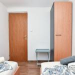 Zwei Betten mit Bettwäsche, Kleiderschrank und Tür im Zimmer.