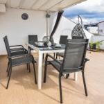 Terrasse mit Esstisch, Stühlen und Hängesessel. Holzfußboden und weißer Wand.