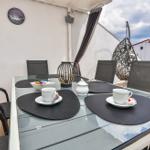 Terrasse mit Glastisch, Stühlen und Hängesessel. Esstisch mit Tassen und Untertassen.