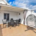Terrasse mit Esstisch, Stühlen und Hängesessel unter Dach.