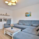 Wohnzimmer mit grauem Sofa, Holztisch und Wandbild.