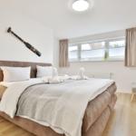 Schlafzimmer mit Bett, Nachttisch, Fenster und Wanddekoration.