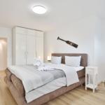 Schlafzimmer mit Bett, Kleiderschrank und Nachttisch. Wanddekoration und Bodenbelag sichtbar.