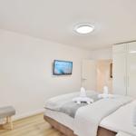 Schlafzimmer mit Bett, Kleiderschrank und Wandfernseher.