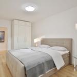 Schlafzimmer mit Bett, Kleiderschrank und Glasnachttisch.
