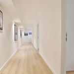 Flur mit Holzboden und Wandbildern, Blick in Schlafzimmer mit Bett.