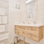 Badezimmer mit Holzwaschbecken, Spiegel und Handtuchheizung.