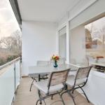Terrasse mit Tisch und Stühlen, Blick auf Bäume und Garten.