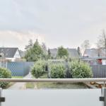 Blick von Balkon auf gepflegten Garten mit Bäumen und Nachbarhäusern