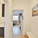 Flur mit Badezimmer und Blick in Wohnbereich mit Fenster.
