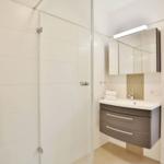 Badezimmer mit Dusche, Waschbecken und Spiegelschrank.