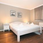 Schlafzimmer mit Bett, Nachttischen und Gardinen.