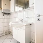 Badezimmer mit Waschbecken, Spiegel und Heizung.