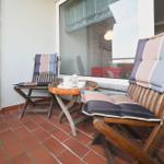 Terrasse mit zwei Holzstühlen, Tisch und rotem Fliesenboden.