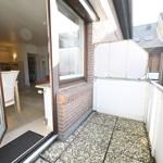 Balkon mit Steinplatten und Blick in Wohnraum mit Essbereich.