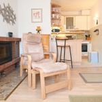 Wohnzimmer mit Sessel, Kamin und Blick in die Küche.