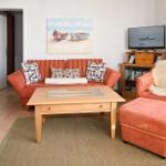 Wohnzimmer mit Sofa, Sessel und Fernseher. Wandbild mit Booten.