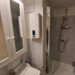 Badezimmer mit Dusche, Waschbecken und Spiegelschrank