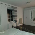 Schlafzimmer mit Bett, Kleiderschrank und Fenster.