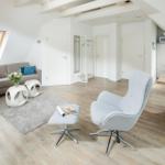 Wohnbereich mit Sofa, Sessel und Essbereich unter Dachschrägen.