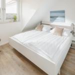Schlafzimmer mit Doppelbett, Fenster und Nachttisch.