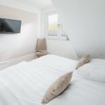 Schlafzimmer mit Doppelbett, Wand-TV und Fenster.