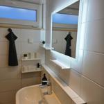 Badezimmer mit Waschbecken, beleuchtetem Spiegel und Fenster.