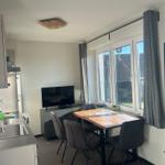 Küche, Essbereich mit Tisch und Stühlen, Fernseher und Fenster.