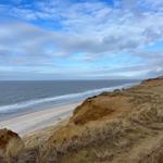 Meerstrand mit Dünen und blauem Himmel mit weißen Wolken.
