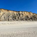 Weiterer Blick auf die weiße Sandküste mit steilen Felsformationen im Hintergrund.