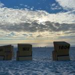 Strand mit Liegestühlen, nummeriert und Blick auf Meer und Himmel.
