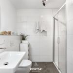 Badezimmer mit Dusche, Waschbecken und Heizkörper