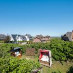 Zwei Strandkörbe stehen im Grün, Häuser im Hintergrund.