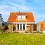 Haus mit orangefarbenem Dach und Garten. Nebenhaus und Holzschuppen sind sichtbar.
