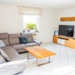 Wohnzimmer mit Sofa, Fernseher und Kaminofen.