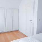 Schlafzimmer mit weißem Schrank, Bett und Holzboden.