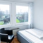 Schlafzimmer mit Bett, Stuhl und Fensterblick auf Garten