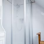 Duschkabine mit Glaswand und Duschbrause in weißer Fliesenwand